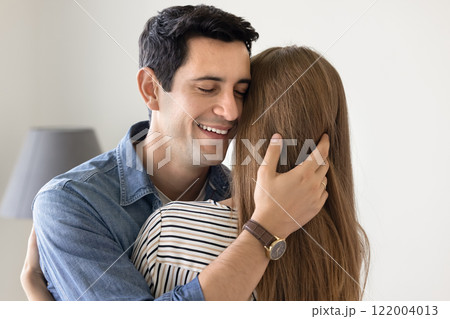 Happy handsome Latin man hugging girl friend with closed eyes 122004013