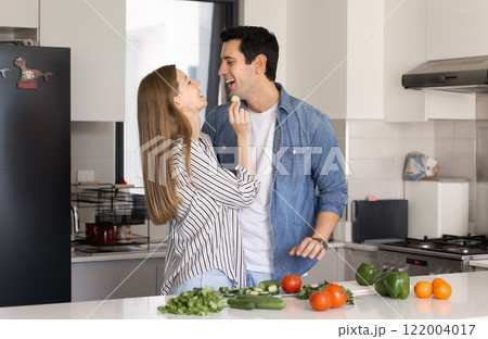 Young couple cooking healthy vegan salad from fresh organic food 122004017