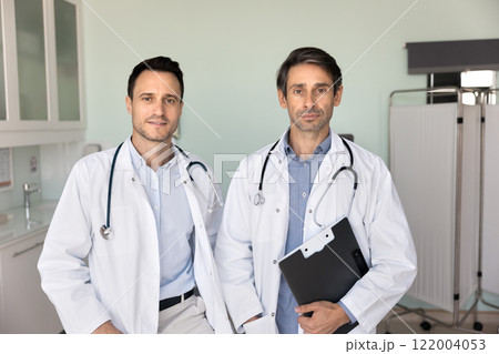 Two confident male doctor colleagues with stethoscopes posing together 122004053