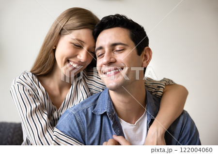 Positive sweet young couple in love hugging with tenderness 122004060