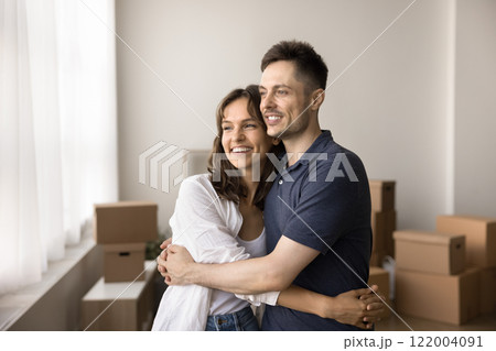 Couple hugging, looking out window, resting on moving day 122004091