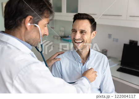 Middle aged Latin practitioner applying stethoscope to chest of patient Middle aged Latin practitioner applying stethoscope to chest of patient 122004117