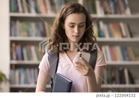 Focused adolescent female student hold cell use wifi at library Focused adolescent female student hold cell use wifi at library 122004132