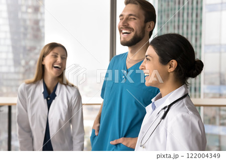 Three multiethnic doctors in uniforms, laughing, sharing lighthearted moments 122004349