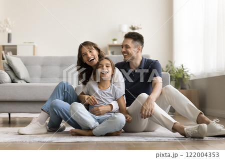 Happy family relaxing seated on warm floor in living room 122004353