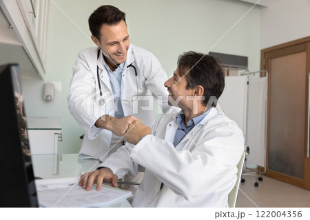 Two happy male doctors giving high five in clinic office 122004356