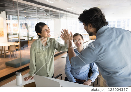 Indian business colleagues giving high five at diverse team meeting 122004357