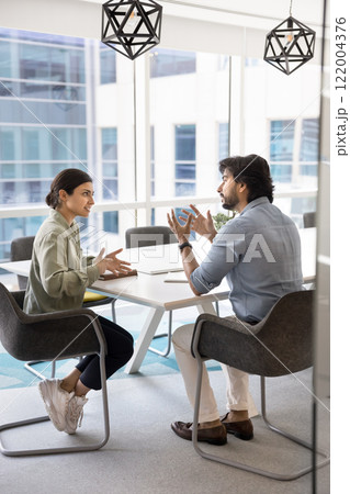Two young Indian business partners engaged in conversation 122004376