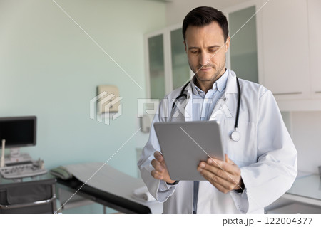 Focused male sonography doctor keeping records on tablet Focused male sonography doctor keeping records on tablet 122004377