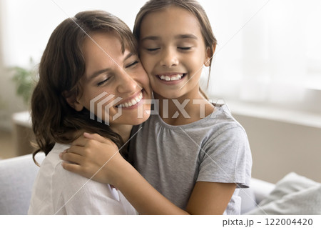 Close up of lovely little girl cuddling tightly her mother 122004420