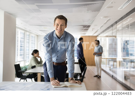 Positive confident business leader man posing in open office Positive confident business leader man posing in open office 122004483