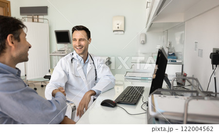 Happy sonographer doctor shaking hands with male patient 122004562