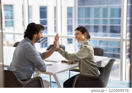Two happy young Indian colleagues giving high five symbolizing cooperation 122004578