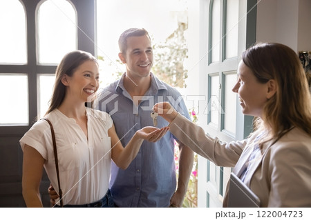 Agent woman giving key from new home to happy homeowners Agent woman giving key from new home to happy homeowners 122004723