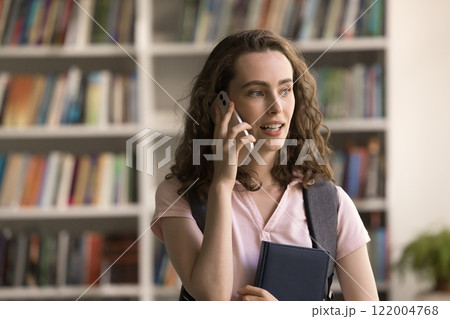 Focused teen girl student speak on phone calling from library Focused teen girl student speak on phone calling from library 122004768
