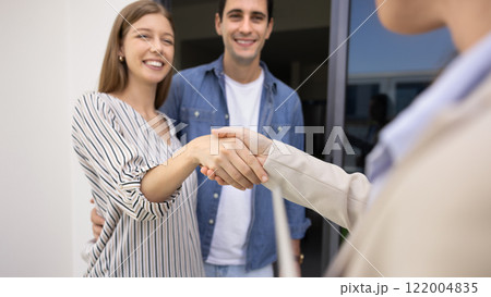 Happy couple of new homeowners shaking hand with realtor woman Happy couple of new homeowners shaking hand with realtor woman 122004835