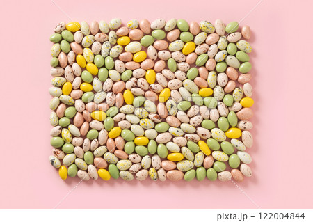 Easter frame of yellow, white and pink chocolate candy sweets as eggs. Food background. Religion tradition. Abstract pattern. View from above. 122004844