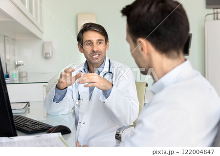 Middle aged Latin doctor meeting with colleague at workplace 122004847