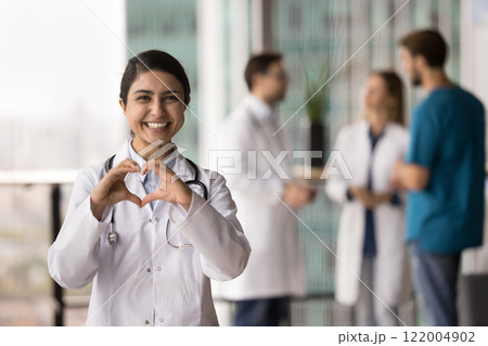 Female doctor showing heart shape with joined fingers Female doctor showing heart shape with joined fingers 122004902