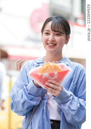 大阪の道頓堀で名物のたこせんを食べ歩きする女性 122004929