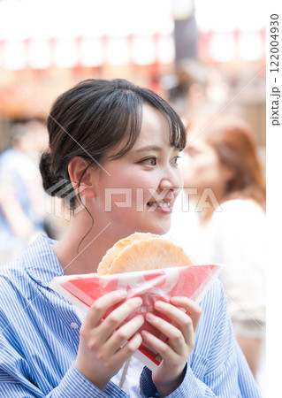 大阪の道頓堀で名物のたこせんを食べ歩きする女性 122004930