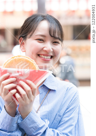 大阪の道頓堀で名物のたこせんを食べ歩きする女性 122004931