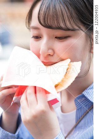 大阪の道頓堀で名物のたこせんを食べ歩きする女性 122004935