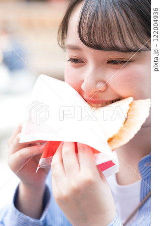 大阪の道頓堀で名物のたこせんを食べ歩きする女性 大阪の道頓堀で名物のたこせんを食べ歩きする女性 122004936