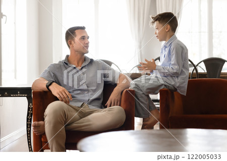 Positive handsome dad talking to son kid at home Positive handsome dad talking to son kid at home 122005033