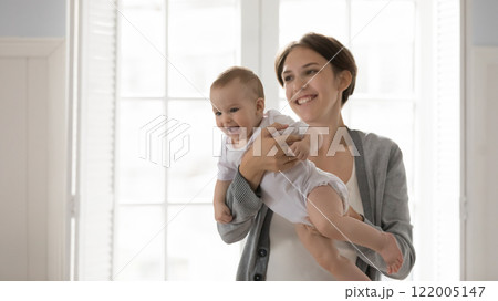Happy excited little infant kid sit on caring mommy hands Happy excited little infant kid sit on caring mommy hands 122005147