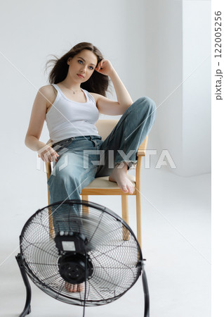 Young woman refreshing with a fan during summer heatwave Young woman refreshing with a fan during summer heatwave 122005256