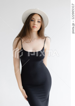 Girl with long hair with white hat is standing on white studio background Girl with long hair with white hat is standing on white studio background 122005317