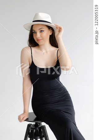 Fashion model posing wearing white hat and black dress 122005319