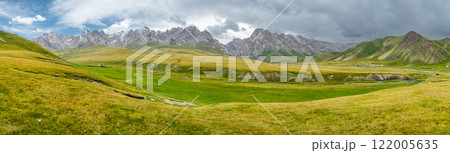 panorama of wide green valley in highlands of kyrgyzstan high mountains in the background, countryside suitable for grazing cattle 122005635