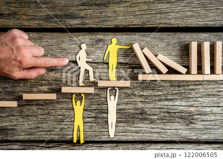 Teamwork and stopping the domino effect concept with paper cutouts of men Teamwork and stopping the domino effect concept with paper cutouts of men 122006505