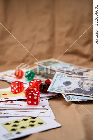 Poker deck spread out on a table with a pile of different dice and dollars. 122006601