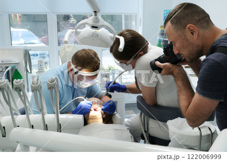 photographer takes pictures of dental treatment process videographer shoots video man Dental treatment. Woman on dental examination. Professional equipment in dental clinic photographer takes pictures of dental treatment process videographer shoots video man Dental treatment. Woman on dental examination. Professional equipment in dental clinic 122006999