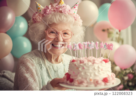 Gray-haired grandmother holding birthday cake and balloons 122008323
