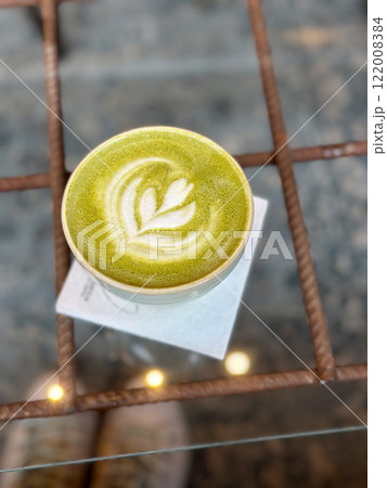 Cup of vibrant green matcha latte with artistic foam design captured from above. Creating a cozy and inviting mood in coffee shop Cup of vibrant green matcha latte with artistic foam design captured from above. Creating a cozy and inviting mood in coffee shop 122008384