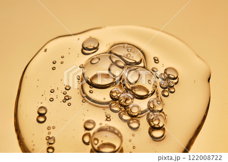 A beautiful drop of gel-like cosmetic serum with bubbles on a golden background. 122008722