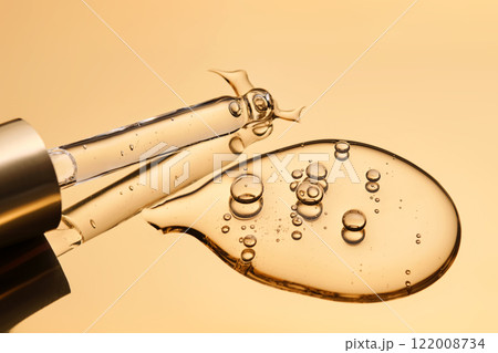 A beautiful drop of gel-like cosmetic serum with bubbles on a golden background. 122008734