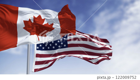 Canada and american national flags waving in the wind on a clear day Canada and american national flags waving in the wind on a clear day 122009752
