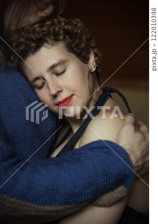 Embrace shared in a cozy indoor setting during an intimate moment between partners 122010398