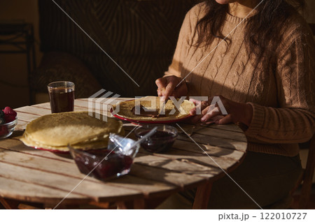 Woman Preparing Pancakes with Spreads During a Daytime Meal 122010727