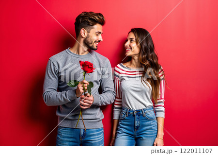 A man and a woman standing next to each other holding a rose A man and a woman standing next to each other holding a rose 122011107