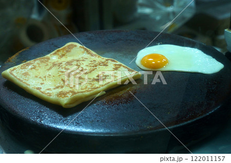 Flatbread cooking beside a fried egg in a busy kitchen Flatbread cooking beside a fried egg in a busy kitchen 122011157