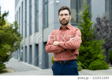 Serious confident businessman outside office building, successful man looking at camera with arms crossed. Serious confident businessman outside office building, successful man looking at camera with arms crossed. 122011265