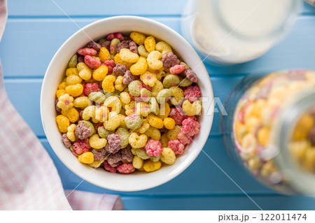 Colorful breakfast cereals in the shape of various fruit in bowl on blue table. Top view. Colorful breakfast cereals in the shape of various fruit in bowl on blue table. Top view. 122011474