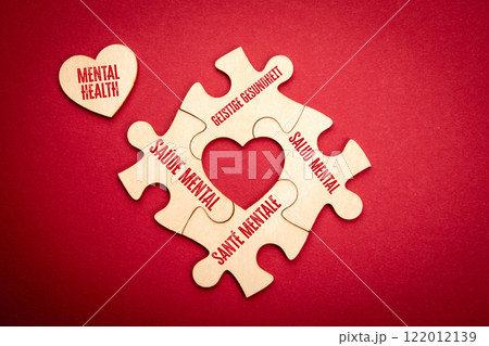 MENTAL HEALTH. Spanish Portuguese German French. Wooden puzzle in the shape of a heart on a red MENTAL HEALTH. Spanish Portuguese German French. Wooden puzzle in the shape of a heart on a red 122012139