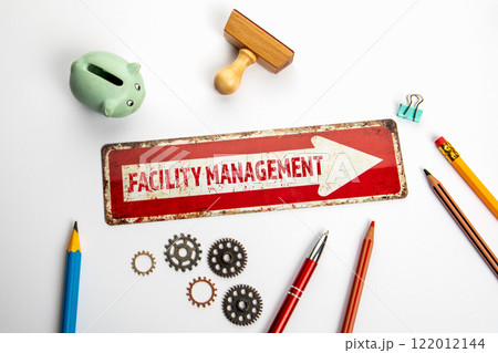 FACILITY MANAGEMENT. Red direction arrow with text on white office desk FACILITY MANAGEMENT. Red direction arrow with text on white office desk 122012144